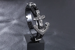Detail of nautical anchor and skull charms on a black braided rope bracelet