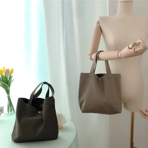 Detail of canvas tote bags with metal snap closure in olive green and khaki colors