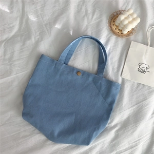 Detail of light blue corduroy tote bag featuring a vintage bronze metal snap button closure