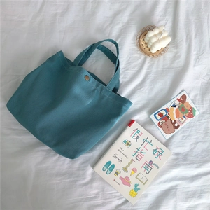 Detail of teal canvas tote bag with diagonal twill texture and bronze metal snap button