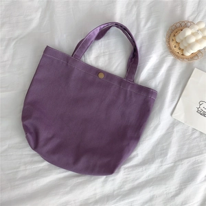 Top view of purple twill canvas tote bag with metal buckle on white textured background