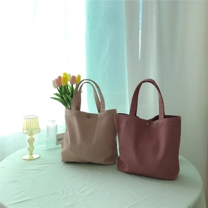 Close-up of canvas texture and metallic snap button on Morandi tone small handbags