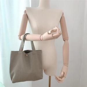 Detail of grey twill canvas tote bag featuring a round button closure and sturdy handle