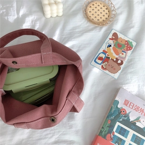 Detail view of pink corduroy tote bag showing magnetic buckle and green lunch box