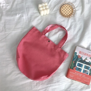 Detail of pink canvas tote bag with metal button closure and twill texture