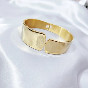 Detailed macro view of wide gold bangle with brushed texture and polished finish hinge