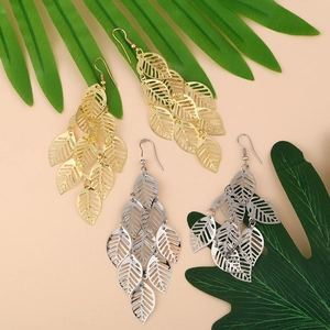 Detailed view of layered gold and silver leaf tassel drop earrings on a tropical leaf background