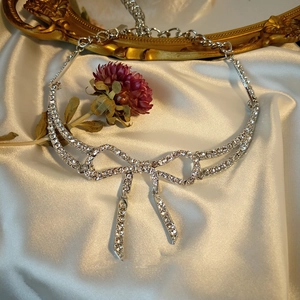 Elegant silver bow pendant necklace with full diamond inlay on luxury silk background