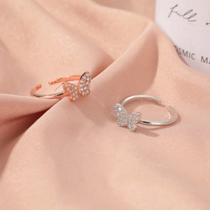 Elegant adjustable butterfly rings with sparkling zircon pavé on pink silk fabric