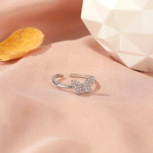 Adjustable silver butterfly ring with sparkling cubic zirconia on pink satin background