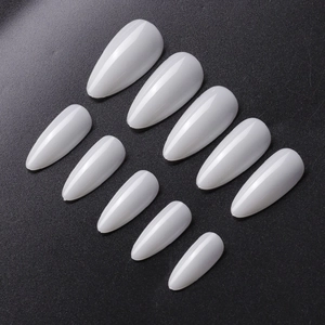 Close-up of ten pieces of glossy milky white stiletto artificial nails on a black background