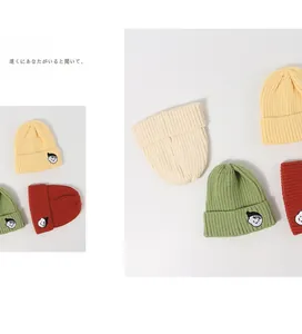 Detailed close-up of knitted beanies featuring original embroidered cartoon boy patch