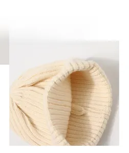 Detailed macro view of the thick ribbed knit texture on a cream-colored children beanie