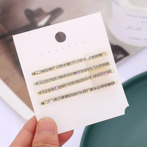 Detailed close-up of four gold hairpins with purple and clear rhinestones on a card