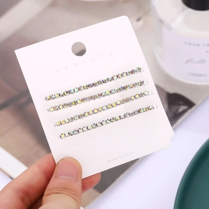 Macro detail of four silver-tone hairpins with iridescent rainbow rhinestones on card