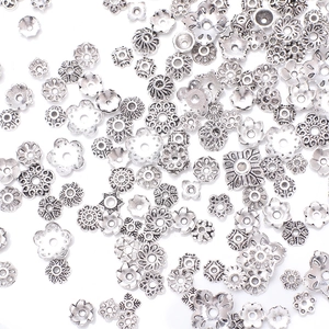 Assorted vintage silver DIY flower spacers and bead caps for jewelry making on white backdrop