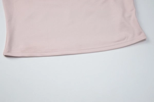 Detailed close-up of light pink knit fabric with professional double-needle stitching hem