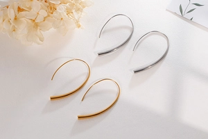Detailed close-up of minimalist U-shaped line earrings in gold and silver metal finish