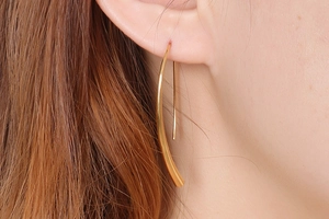 Close-up of minimalist gold teardrop hook earring on female model showing glossy finish