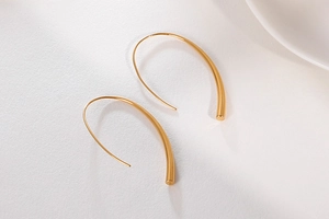 Detail showing polished gold streamlined hook earrings with minimalist U-shaped design