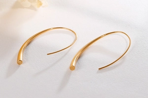 Detailed close-up of golden teardrop earrings with a sleek minimalist curved design