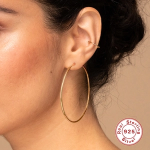 Close-up of gold S925 sterling silver hoop earrings and ear cuff on female model