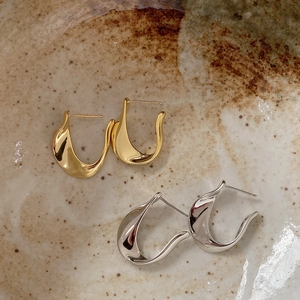 Minimalist U-shaped sterling silver earrings in gold and silver finish on ceramic bowl