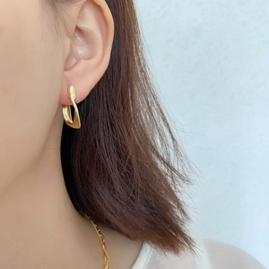 Close-up of golden twist U-shaped stud earrings in 925 sterling silver on model ear