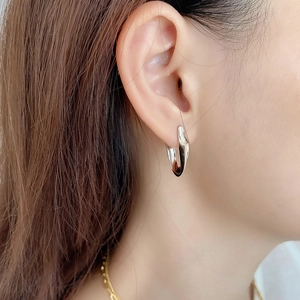 Close-up of polished 925 sterling silver U-shaped hoop earring on model's ear