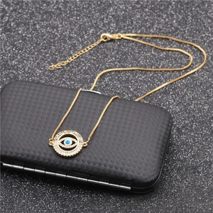 Golden Evil Eye pendant necklace with colorful gemstones on a black textured box