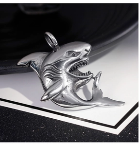 Detailed close-up of a vintage silver shark pendant with sharp teeth and metallic luster