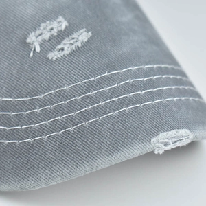 Macro shot of grey washed cotton baseball cap with white triple stitching and distressed brim