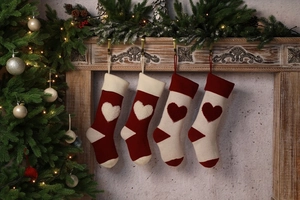 Close-up of four knitted Christmas stockings with 3D hearts hanging on a festive mantel
