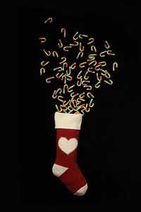 Close-up of red knitted Christmas stocking with 3D white heart and rainbow candy canes