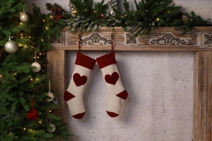 Close-up of knitted Christmas stockings with 3D red heart patterns in cream and burgundy