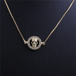 Halloween gold skull pendant necklace with diamond-encrusted circular border on black backdrop