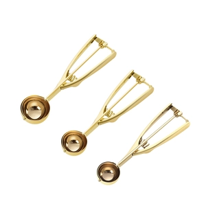 Three golden stainless steel ice cream scoops with spring release on white background