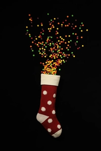 Vue macro créative d'une chaussette de Noël rouge en tricot avec pois 3D remplie de bonbons