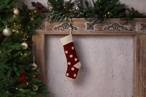 Gros plan d'une chaussette de Noël rouge à pois blancs accrochée à une cheminée décorée
