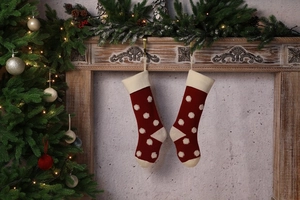 Détail de chaussettes de Noël rouges en tricot avec pois 3D sur cheminée festive