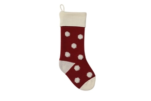 Détail d'une chaussette de Noël en tricot rouge avec pompons blancs et laine épaisse