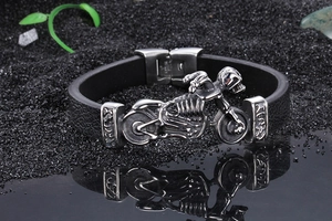 Detailed view of silver motorcycle skull bracelet with black leather band on dark stone