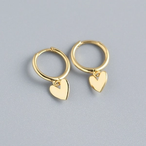 Macro shot of gold heart dangle hoop earrings in 925 sterling silver on grey background