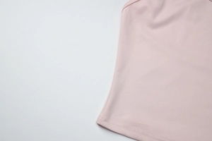Detail of light pink knit top featuring durable double-needle stitching on the hemline