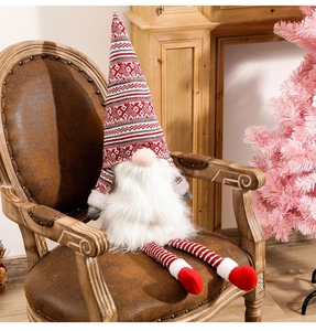 Close-up of a Christmas gnome doll with red striped hat on a vintage leather chair