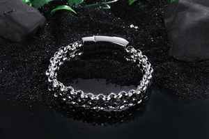 Close-up of industrial steel chain bracelet with large magnetic clasp on black sand