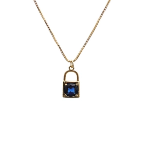 Macro shot of gold lock pendant necklace with a square blue zircon gemstone detail