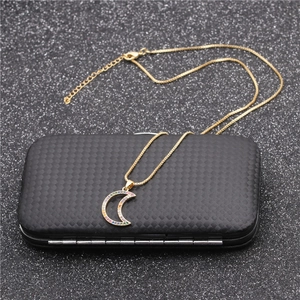 Golden necklace with rainbow zircon moon pendant displayed on a black textured jewelry box