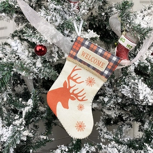 Plaid Christmas stocking with reindeer and snowflake print on a snowy tree