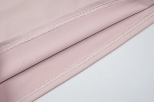 Detailed close-up of double-needle hem stitching on pink knit fabric set